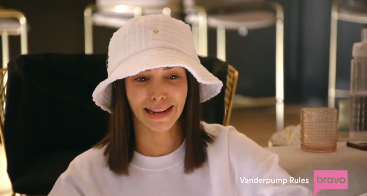 a white girl with brown hair cries while wearing a large white bucket hat