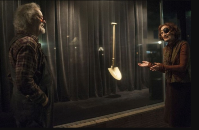 a woman in an eyepatch gestures toward a golden shovel to an old man in plaid on the tv show Twin Peaks