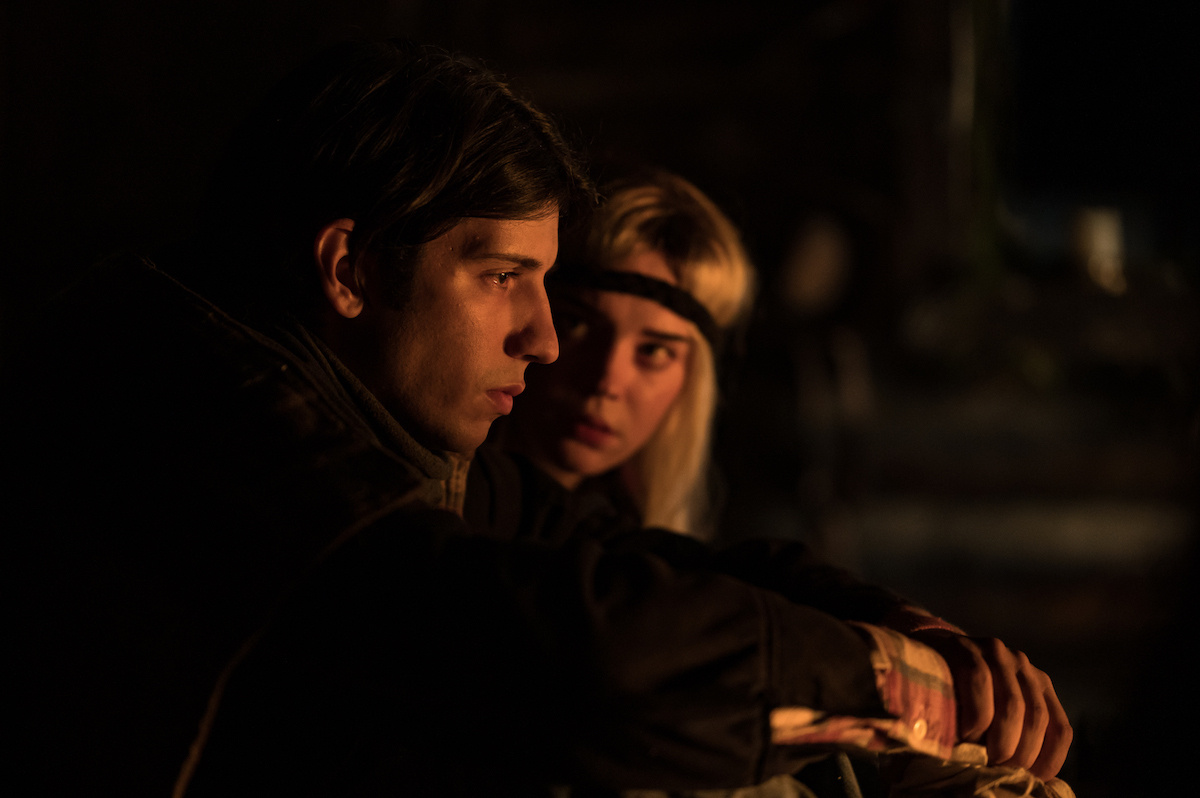 (L-R): Kevin Alves as Teen Travis and Sophie Thatcher as Teen Natalie in YELLOWJACKETS Season 2 talking in the cabin. Photo Credit: Kailey Schwerman/SHOWTIME.