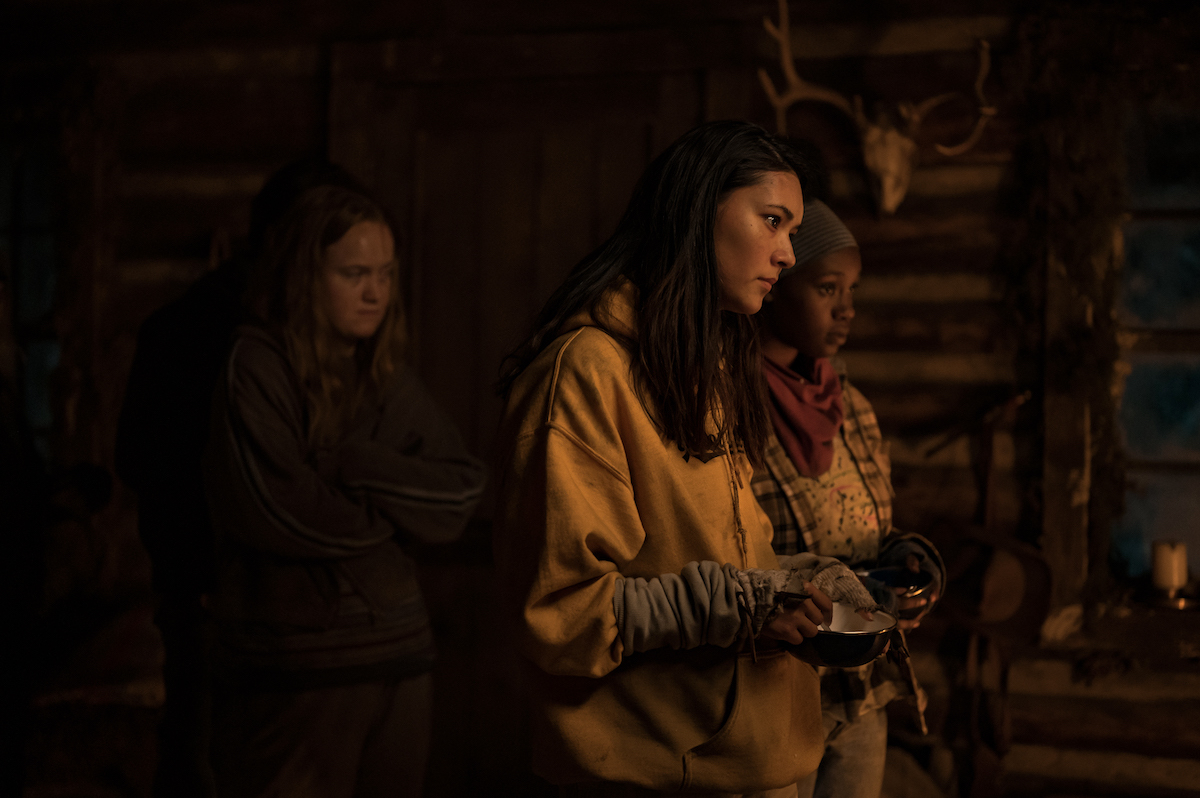 (L-R): Liv Hewson as Teen Van, Alexa Barajas as Teen Mari and Nia Sondaya as Teen Akilah in YELLOWJACKETS Season 2 are in the cabin, looking at something. Photo Credit: Kailey Schwerman/SHOWTIME.