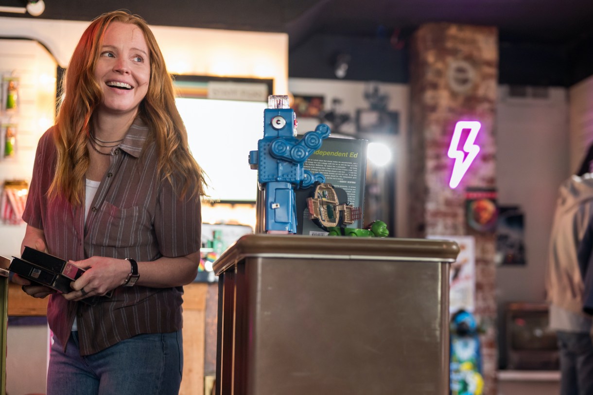 Lauren Ambrose as Van in YELLOWJACKETS Season 2 smiles near a podium. Photo Credit: Kailey Schwerman/SHOWTIME.