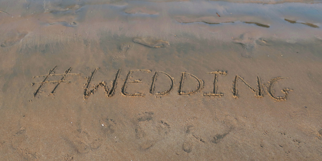 #WEDDING written into the sand on a beach