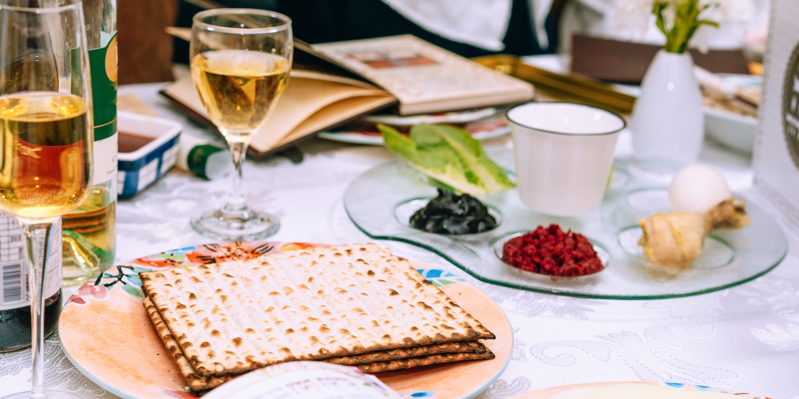 Passover table setting with a traditional Passover seder plate with symbolic meal, matzah and Haggadah.