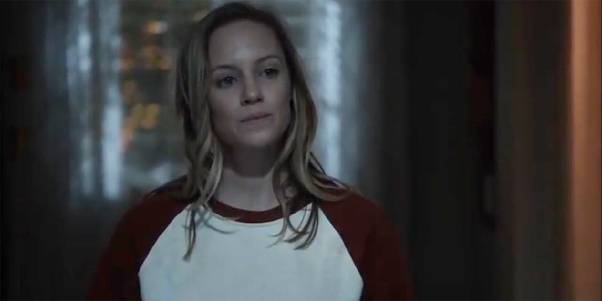 Maya in a long-sleeve baseball ringer-tee, standing in the doorway in the dark, on Station 19