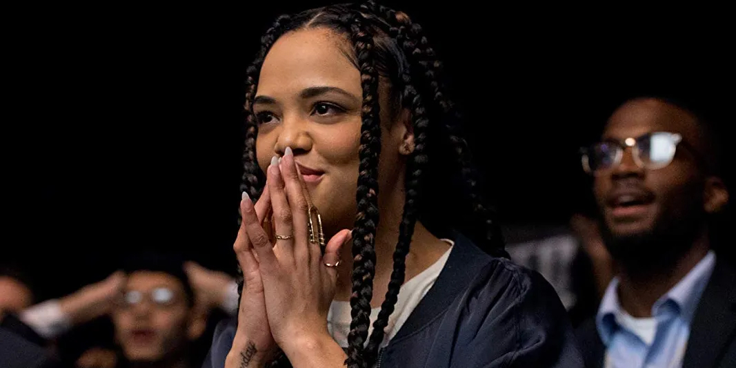 Tessa Thompson has long braids as Bianca in Creed, her hands are covering her mouth as she looks on in anticipation.