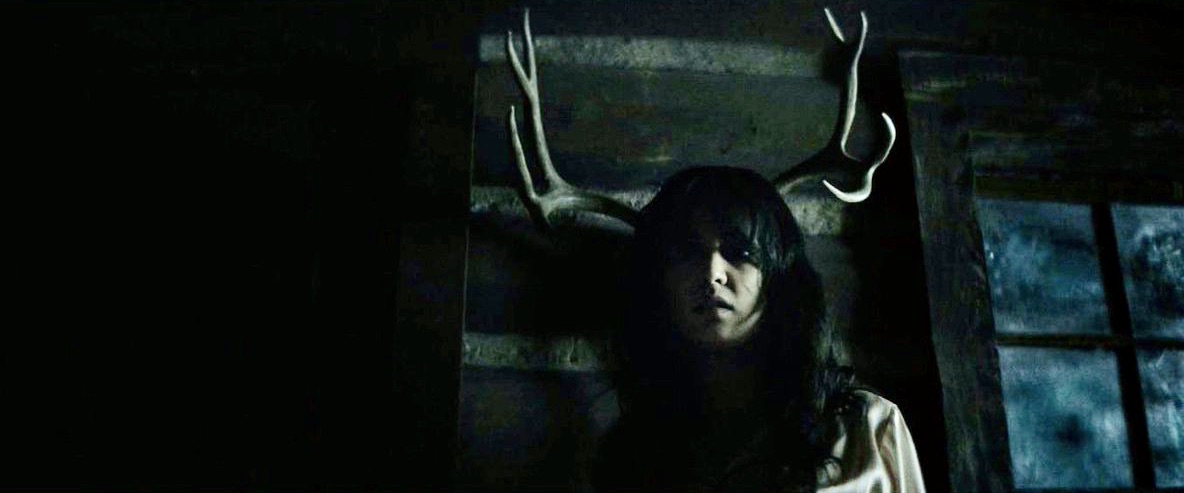 Lottie in a cabin with antlers behind her head