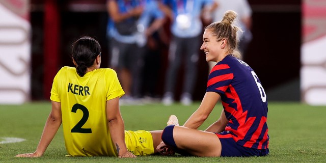 Sam Kerry and Kristie Mewis sit beside each other on the soccer field in their national team jerseys
