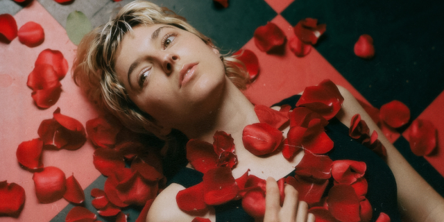 Caroline Rose on a black and red checked floor with rose petals on them