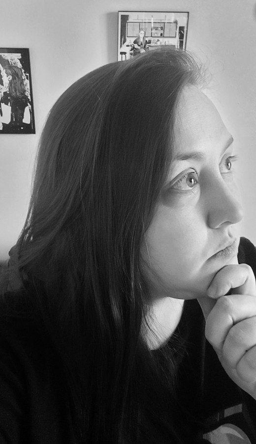 a black and white photo of valerie, a white woman, hand on her chin, with long hair.