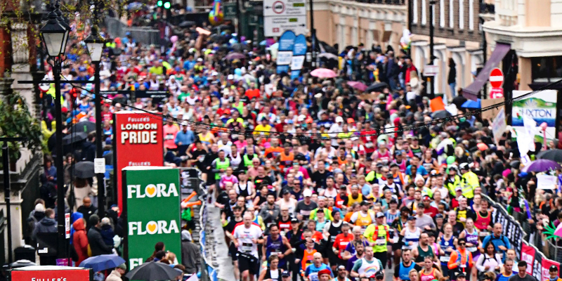 A far away shot of the London Marathon where the crowd just looks like a mass of pink. To the left a red sign is visible that says "London Pride."
