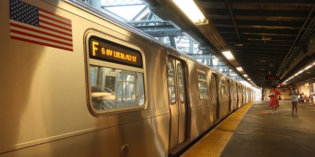 A F train subway car pulling into the station.