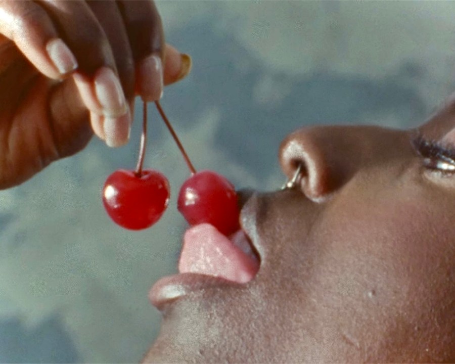 A black queer person eating cherries.
