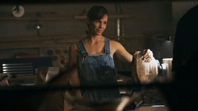 Hannah in overalls without a shirt under them, exposing her perfect arms