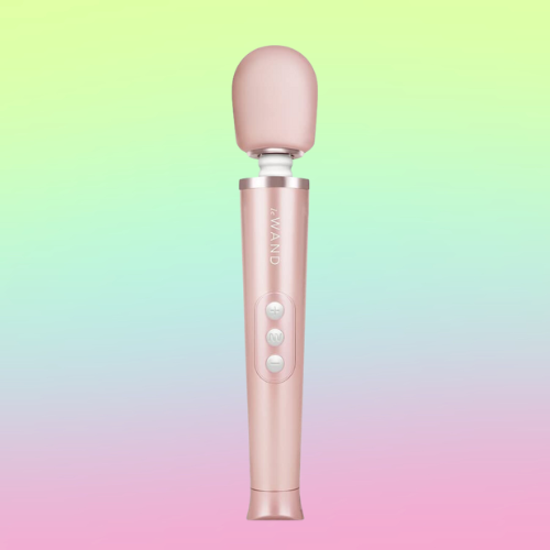 Against a green, blue, and pink ombre background, there is the Le Wand, a rose gold wand vibrator with three silver buttons on the handle.