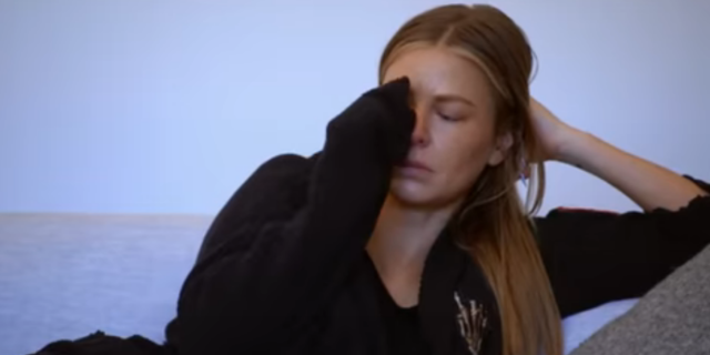 Ariana Madix dabbing at her eye while crying on a couch in the Vanderpump Rules season finale trailer
