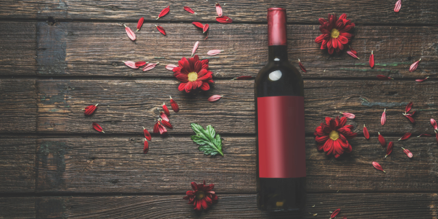 a red wine bottle with a blank red wine label surrounded by flowers