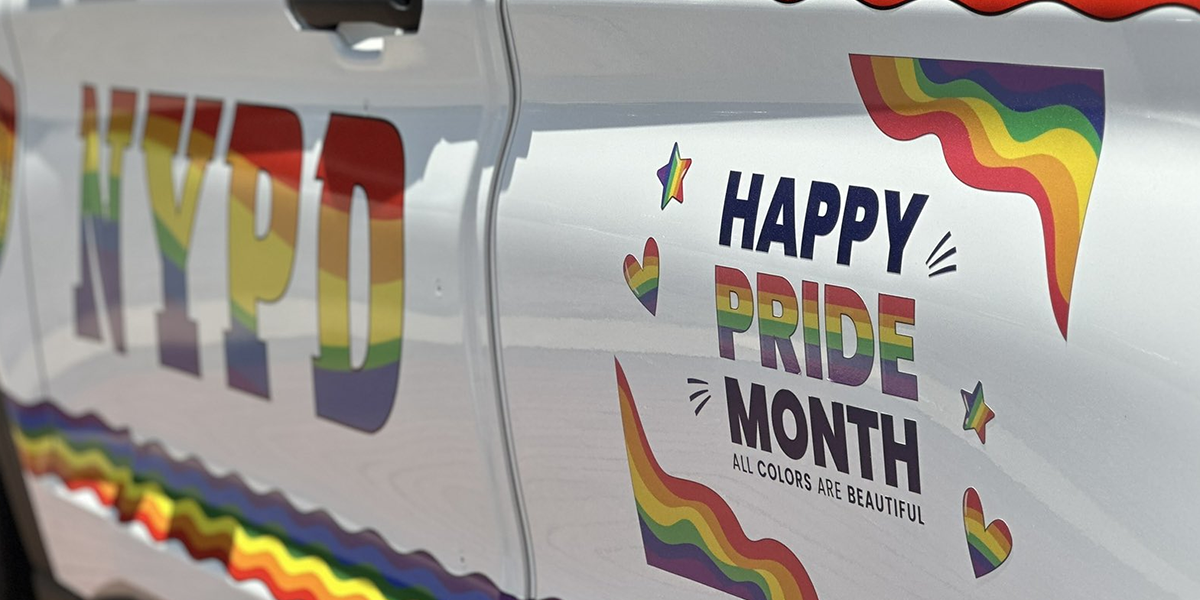 An NYPD cop car that says HAPPY PRIDE MONTH! ALL COLORS ARE BEAUTIFUL!