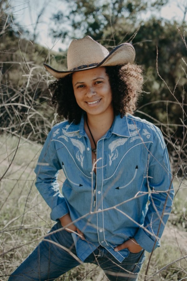 Kimber wears a cowboy hat and a blue Western style buttondown