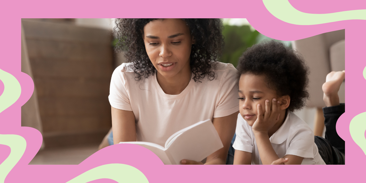 a Black mom reads a book to her son while they lay on the floor