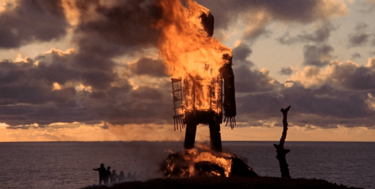 a screenshot from The Wickerman showing the giant wickerman burning against a sunrise sky