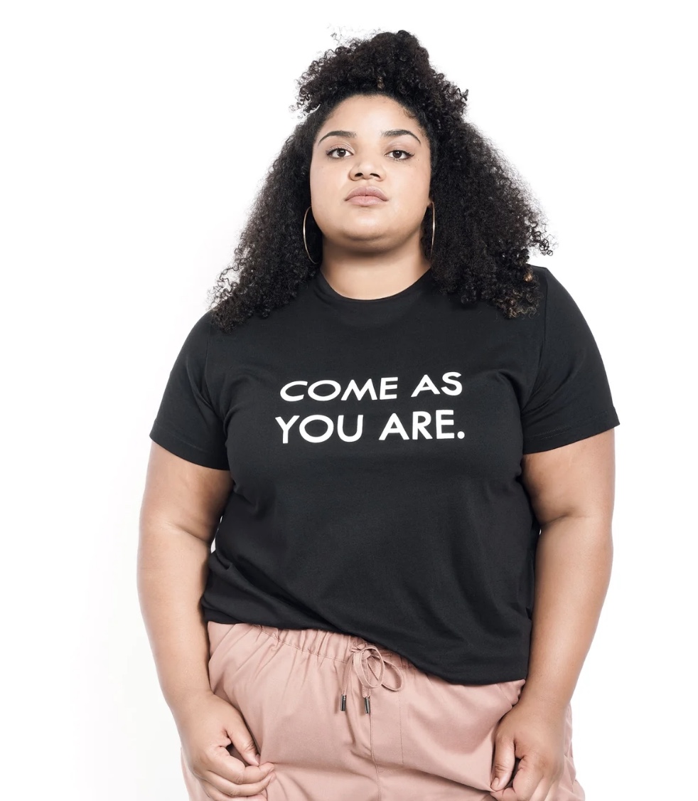 Model in a black tee that reads "Come As You Are"