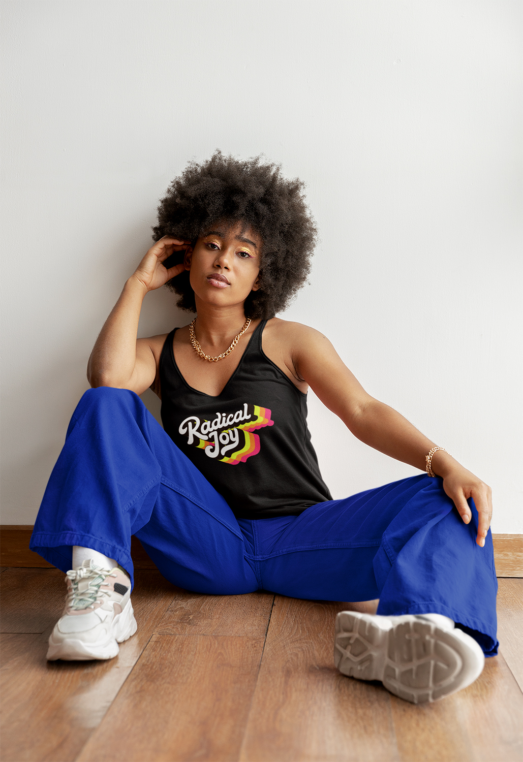woman in a black tank top that reads "Radical Joy" with blue pants