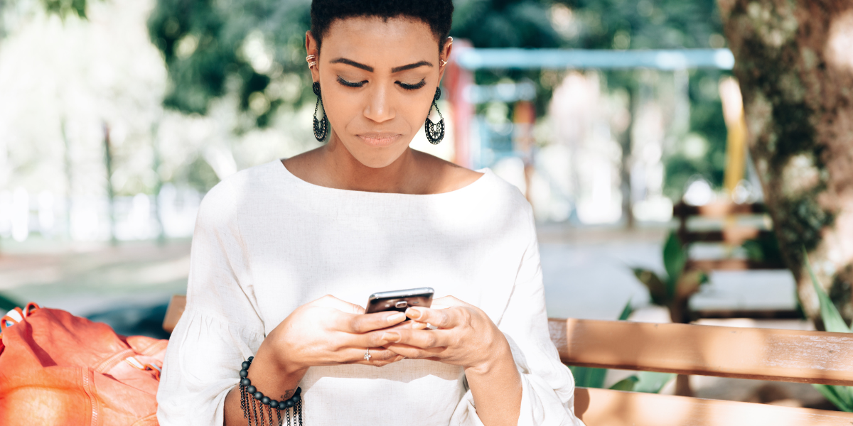 a woman with short brown hair texts on her phone with pursed lips