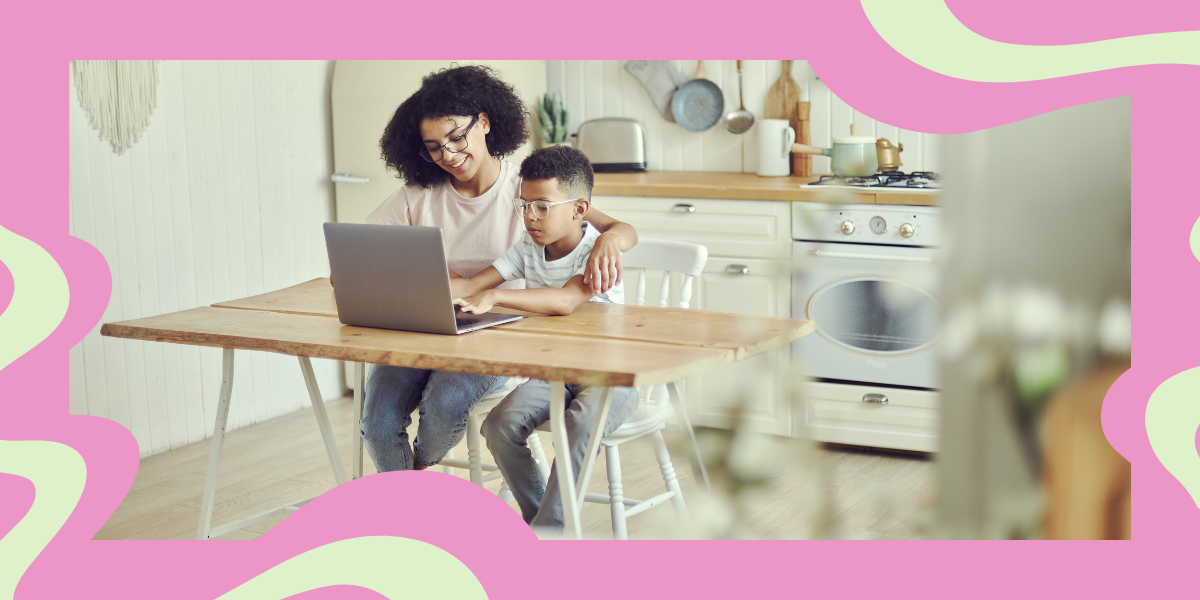 a mom sits at the kitchen table with her son, and they're both looking at a laptop