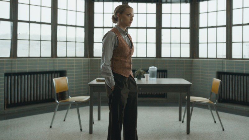 The Crowded Room: Amanda Seyfried as Rya in a vest with her hands in her slack pockets and her hair in a low bun