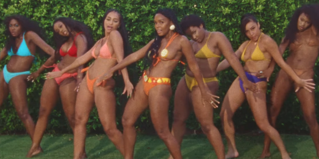 Janelle Monáe and their backup dancers in the music video for Water Slide, all clad in bright colored bikinis