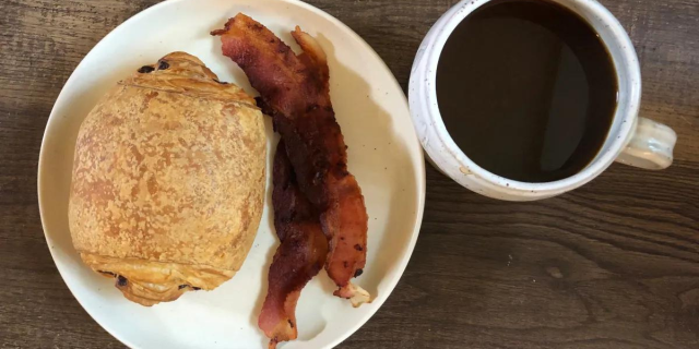 chocolate croissant and bacon next to a mug of coffee