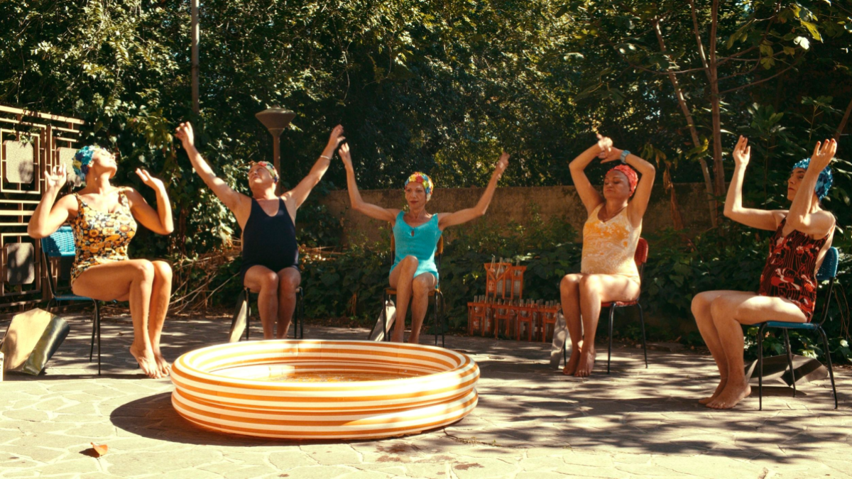 Trans women sit joyfully around an outdoor kiddie pool