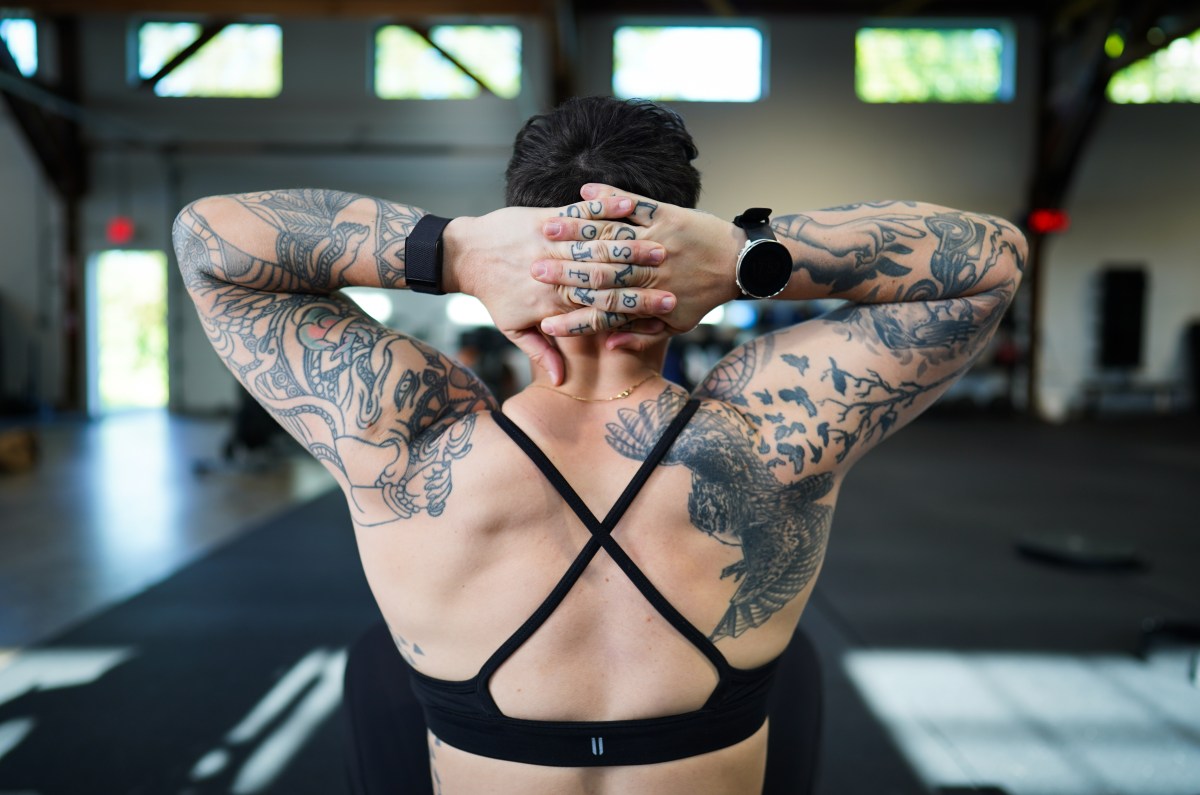 from behind, a shot of a white butch with a lot of tattoos wearing a black sports bra