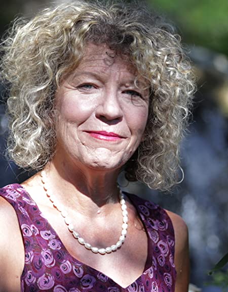 Debi Sundahl with a pearl necklace and purple dress and curly hair