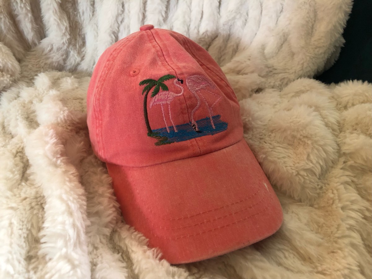 a pinkish hat with flamingos and a palm tree on it