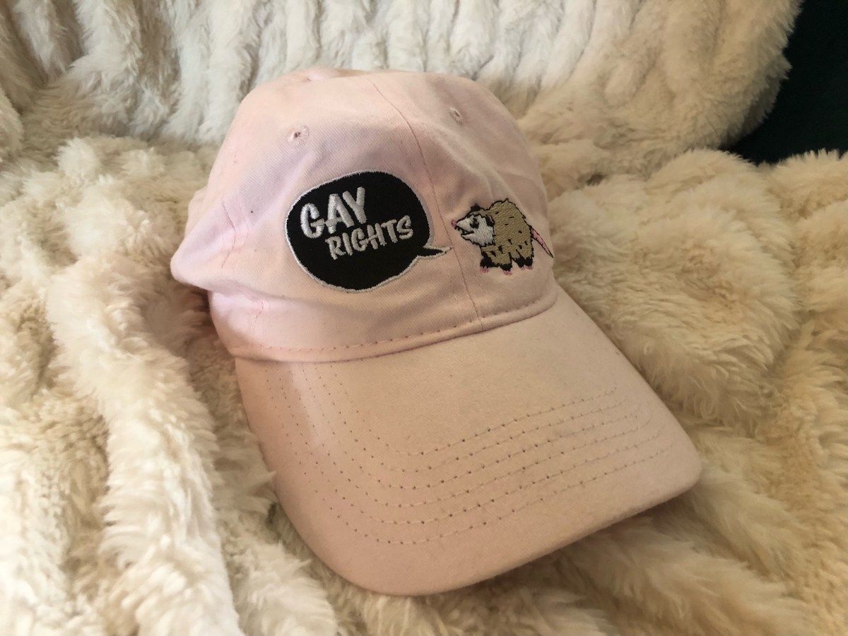a pink hat that says GAY RIGHTS and has a possum on it