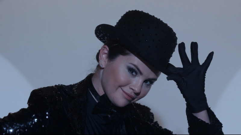 Selena Gomez as Mabel in Only Murders in the Building in a Fosse outfit tipping her hat and smirking at camera.