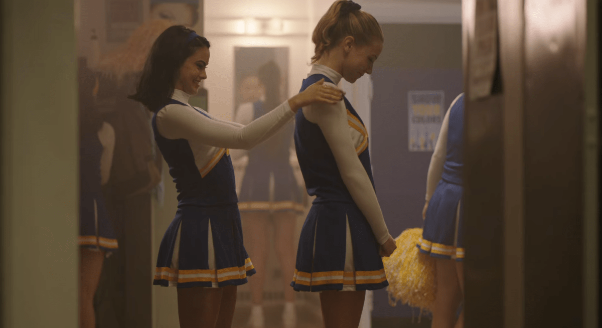 Veronica zips up Betty in her cheerleading uniform on Riverdale.