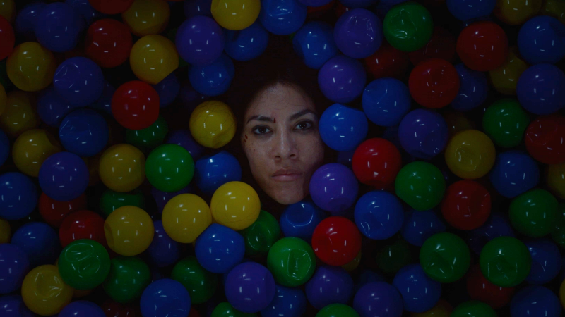 Stephanie Beatriz as Quiet in a ballpit with only her face showing.