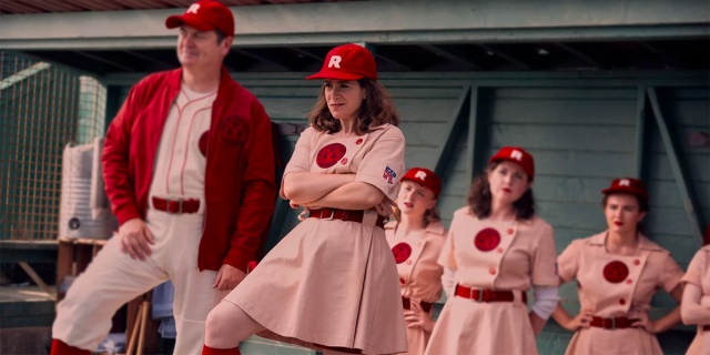 The Rockford Peaches stand in the dugout, with Shaw leading the way with her arms crossed, in A League of Their Own.