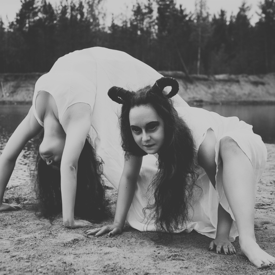 two creepy twins with weird hair contort on the ground in this black and white photo