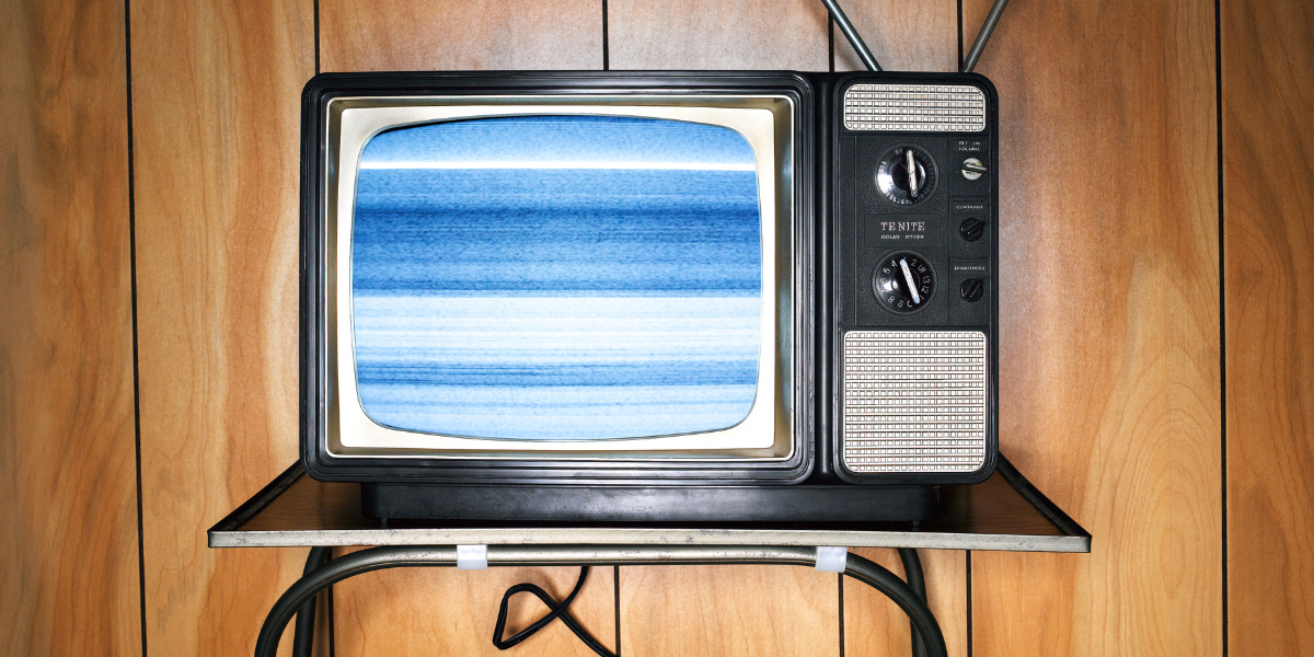 a tv on a stand with a wood paneled wall behind it