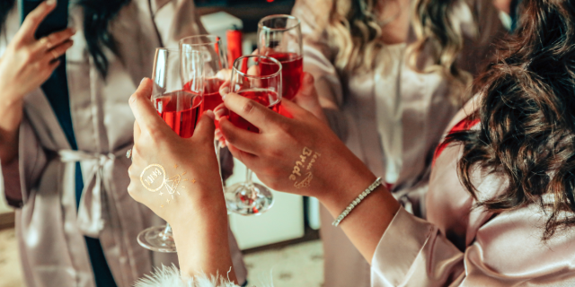 a bachelorette party where a bunch of girls cheers with champagne flutes of red liquid