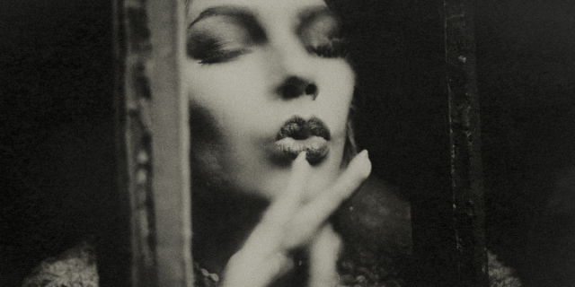 a black and white photo of a woman kissing a windowpane