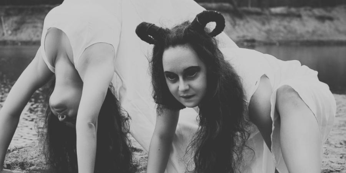 two creepy twins with weird hair contort on the ground in this black and white photo