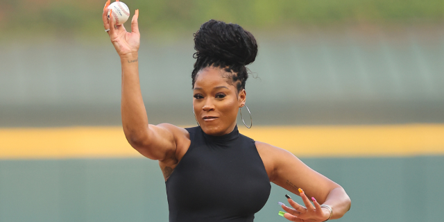 Keke Palmer throwing a baseball in a black tank top with multicolored nails