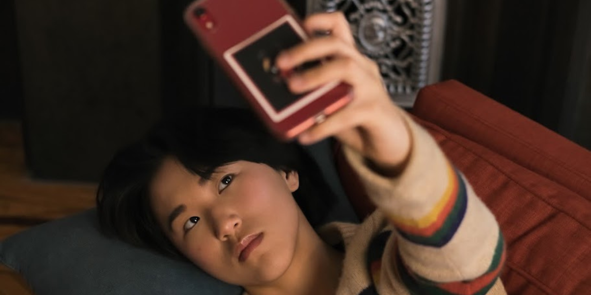 a transmasc person of Asian descent takes a selfie while laying on a couch