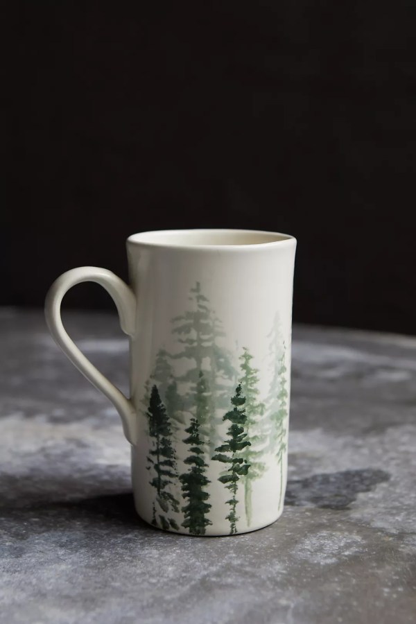 an off white ceramic mug with green trees printed on it