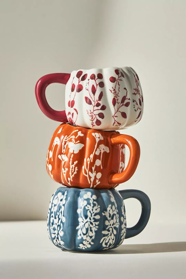 three stacked pumpkin shaped mugs with floral prints on them
