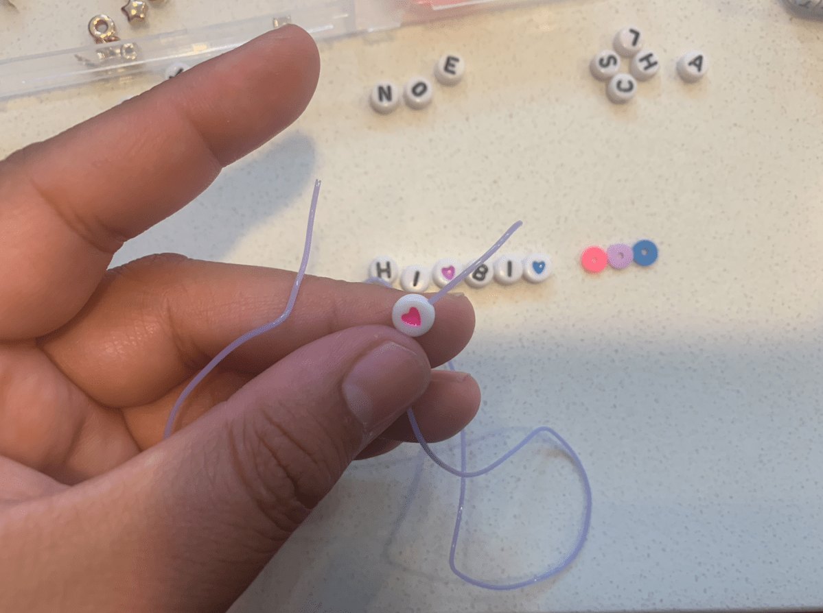 fingers holding string with a heart bead on it